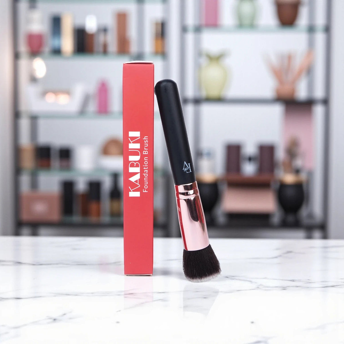 FV Skin Studio Kabuki foundation brush with black handle and rose gold ferrule next to its red product packaging