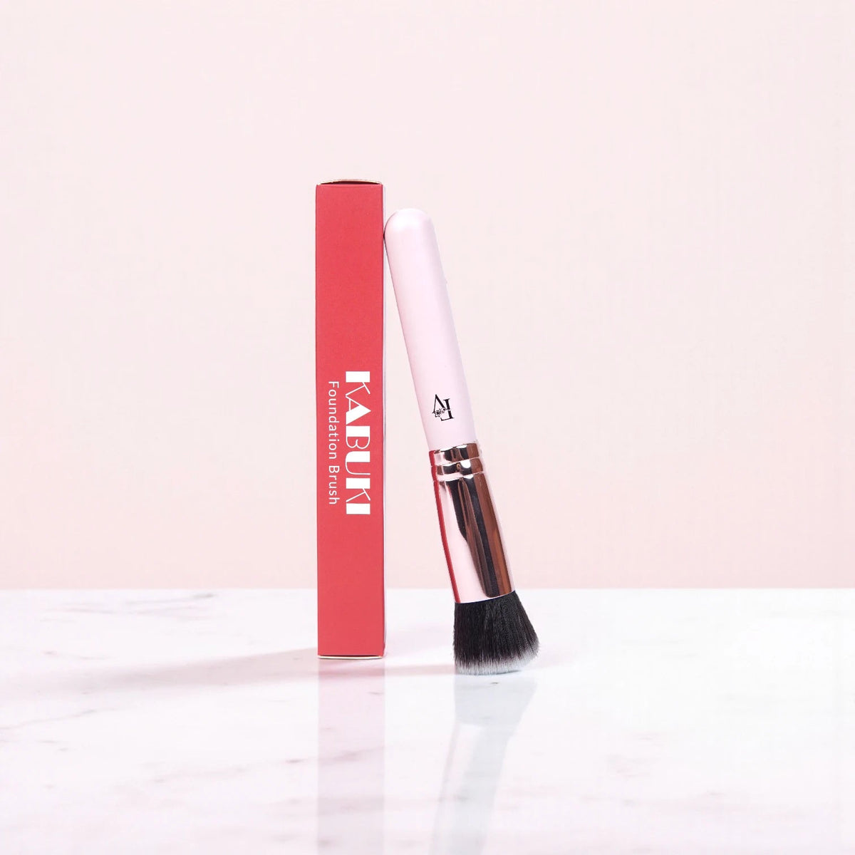 FV Skin Studio Kabuki brush with a light pink handle and soft black bristles, standing next to its red product box.