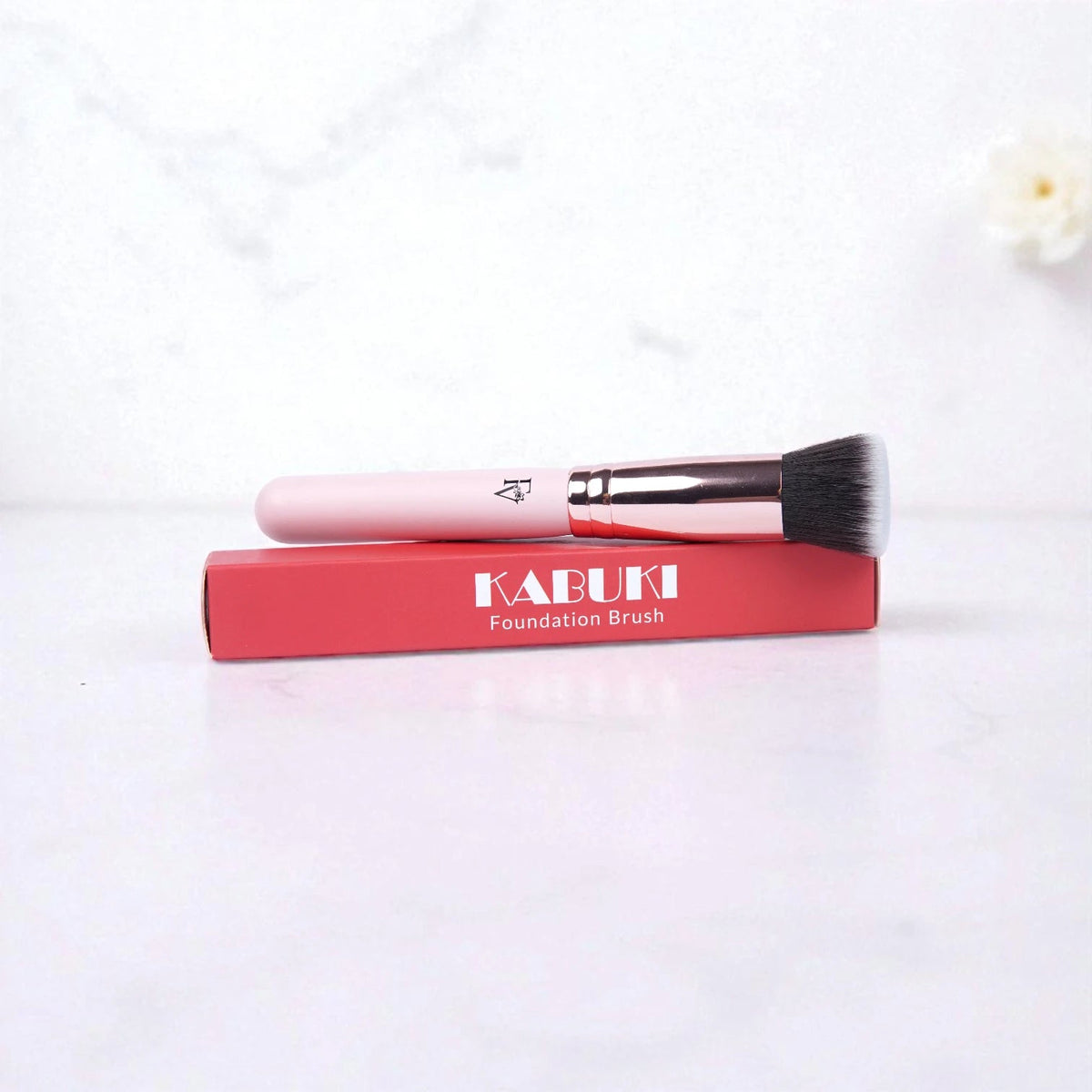 FV Skin Studio Kabuki makeup brush with a soft, dense head and pink handle resting on its red product box.