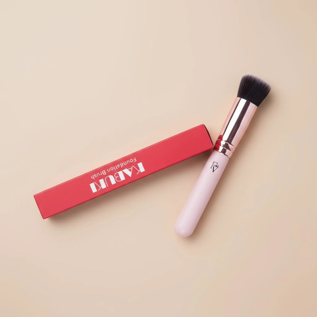 FV Skin Studio Kabuki makeup brush with soft dense bristles and a light pink handle next to its red branded box.