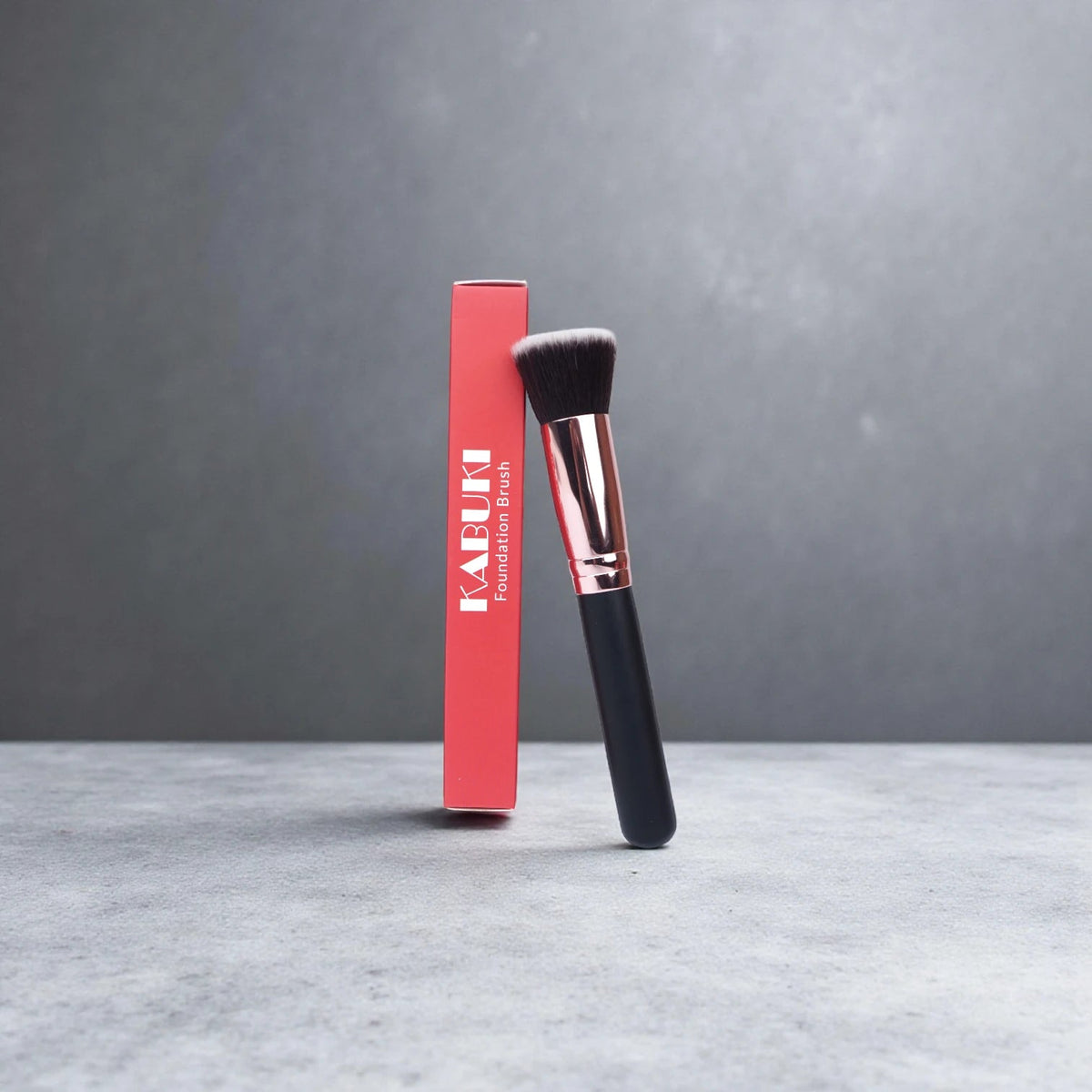 FV Skin Studio Kabuki makeup brush with soft bristles and wooden handle standing next to its red product box